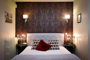 Schlafzimmer mit einem weißen Bett und einem roten Kissen in der Unterkunft Hotel Les Pasteliers in Albi