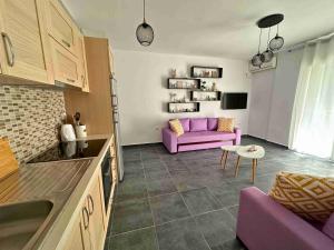 een woonkamer met een paarse bank en een tafel bij Tropicana Apartments in Dhërmi