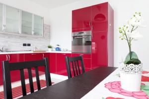 eine Küche mit roten Schränken und einem Tisch mit Stühlen in der Unterkunft A Pochi Passi in Venaria Reale