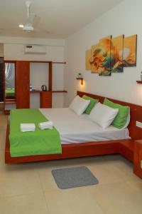 a bedroom with a large bed with green sheets at Traveller's Hotel Hikkaduwa in Hikkaduwa