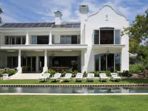 a white house with chairs and a swimming pool at Constantia Klein in Cape Town