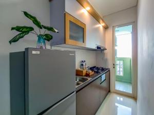 a small kitchen with a refrigerator and a sink at Borneo Bay City Apartment, 1BR in Klandasan Kecil