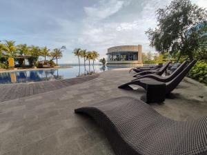 a row of chairs sitting next to a swimming pool at Borneo Bay City Apartment, 1BR in Klandasan Kecil