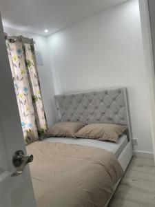 een bed met een hoofdbord en gordijnen in een slaapkamer bij Feltham rest place in Feltham