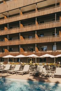 a hotel with lounge chairs and a swimming pool at Faern Crans-Montana Valaisia in Crans-Montana