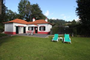a small house with two lawn chairs in the yard at Quinta Das Faias in Camacha