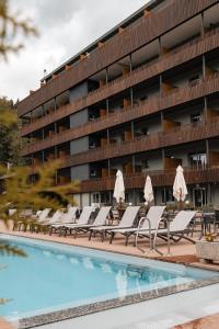 克萊恩 蒙塔納的住宿－Faern Crans-Montana Valaisia，酒店游泳池设有躺椅,酒店大楼