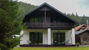 dom z dachem gambrel z krzesłami na ganku w obiekcie Berghaus Bukovel w mieście Bukowel