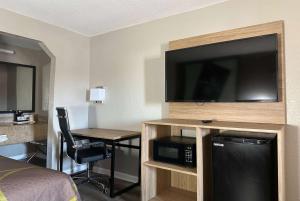 a hotel room with a flat screen tv and a bedroom at Super 8 by Wyndham Monroe in Monroe