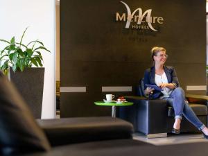a woman sitting in a chair in a room at Mercure Hotel Köln West in Cologne