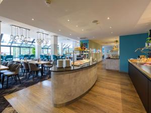 a restaurant with a bar and tables and chairs at Mercure Hotel Köln West in Cologne