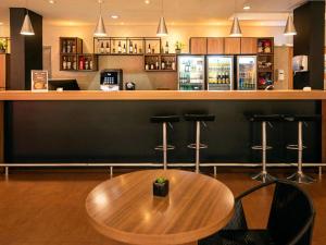 un bar con mesa de madera y taburetes en ibis Betim, en Betim