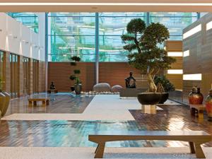 a lobby with a tree in a large building at Sofitel London Heathrow in Hillingdon