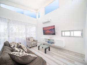 Una sala de estar con un sofá y un televisor. en Amazing 2br Villa Near Surfing Beaches, en Cabarete