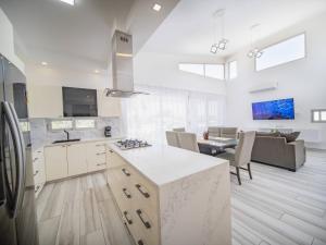 Una cocina con gabinetes blancos y una sala de estar. en Amazing 2br Villa Near Surfing Beaches, en Cabarete