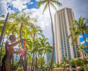 una statua di fronte a palme e edifici di Hyatt Regency Waikiki Beach Resort & Spa a Honolulu