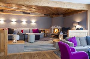 a living room with purple furniture and a fireplace at Hotel Rosatsch in Pontresina