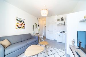 a living room with a blue couch and a kitchen at Le Petit Clément - Charmant et Cosy in Villeurbanne