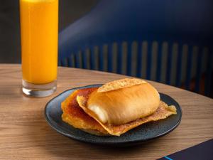 a sandwich on a plate on a table with a glass of orange juice at ibis budget Jundiai Shopping in Jundiaí