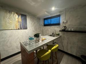 a kitchen with a sink and two yellow chairs at Ipoh Zing Vale - Family & Couple Suite in Ipoh