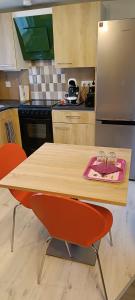 cocina con mesa de madera y 2 sillas de color naranja en Studio à louer, en Clohars-Carnoët