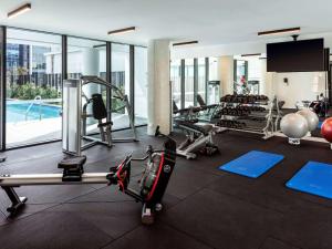a gym with cardio equipment and a swimming pool at Novotel Brisbane South Bank in Brisbane