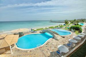 uma vista superior de uma piscina com guarda-sóis e do oceano em Radisson Blu Resort, Fujairah em Dibba