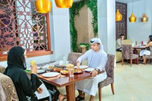 un hombre y una mujer sentados en una mesa comiendo comida en Radisson Blu Resort, Fujairah en Dibba