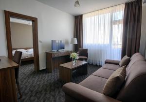 een hotelkamer met een bank en een televisie bij Hotel Magnólia in Piešťany
