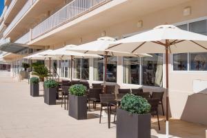 a row of tables with umbrellas in front of a building at Catalonia del Mar - Adults Only in Cala Bona