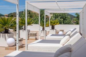 a white patio with white furniture and palm trees at Catalonia del Mar - Adults Only in Cala Bona