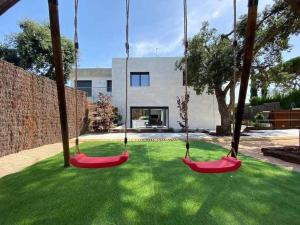 a yard with two swings in front of a house at Naramia Sagaro Villa with Poolgarden10 Pax in S'Agaro