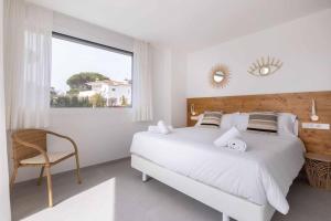 a white bedroom with a large bed and a chair at Naramia Sagaro Villa with Poolgarden10 Pax in S'Agaro