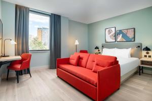 um quarto de hotel com uma cama e um sofá vermelho em Hyatt Place London City East em Londres