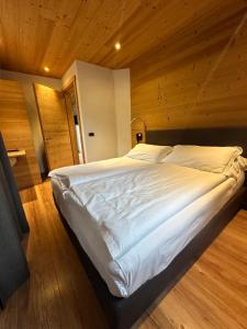 a large white bed in a room with wooden walls at Alpen Hotel Chalet in Valdidentro