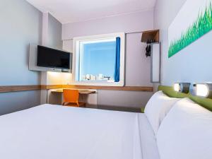 a bedroom with a bed and a desk and a tv at Ibis Budget Fortaleza Praia de Iracema in Fortaleza