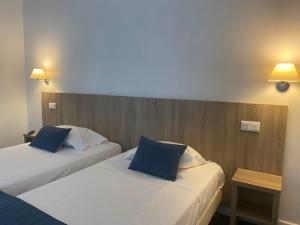 two beds in a hotel room with blue pillows at Grand Hôtel De Calvi in Calvi