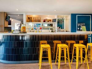a bar with yellow stools in a restaurant at Greet Hotel Bordeaux Floirac Arena in Floirac