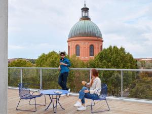 圖盧茲的住宿－Aparthotel Adagio Original Toulouse Centre La Grave，两人坐在阳台,后方是一座建筑