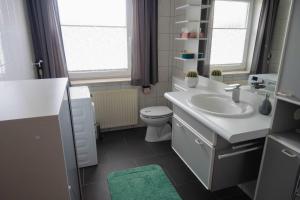 a bathroom with a white sink and a toilet at Ferienhaus Andrea in Westerstede +8 photos