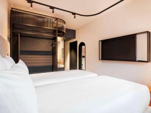 a bedroom with two beds and a flat screen tv at TRIBE Milano Malpensa in Vizzola Ticino