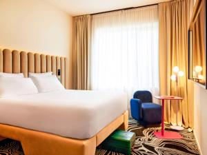 a hotel room with a bed and a chair at TRIBE Milano Malpensa in Vizzola Ticino