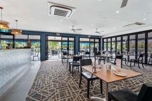 un comedor con mesas, sillas y ventanas en Quality Resort Parkhurst en Rockhampton