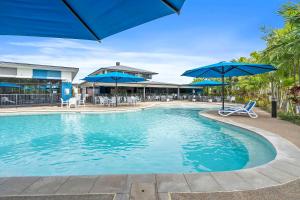 een zwembad met blauwe parasols, stoelen en tafels bij Quality Resort Parkhurst in Rockhampton