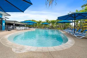 een zwembad met stoelen en blauwe parasols bij Quality Resort Parkhurst in Rockhampton