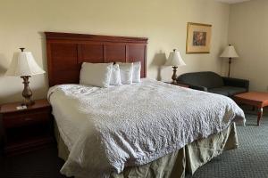 Quality Inn - Norman near University في نورمان: غرفة فندقية فيها سرير وكرسي ومصابيح