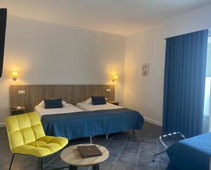 una habitación de hotel con 2 camas y una silla amarilla en Grand Hôtel De Calvi, en Calvi