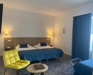 a hotel room with two beds and a yellow chair at Grand Hôtel De Calvi in Calvi +32 photos