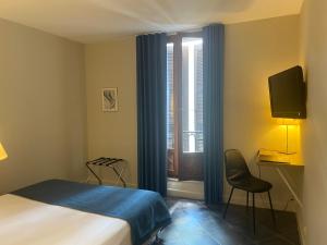 a bedroom with a bed and a window with a tv at Grand Hôtel De Calvi in Calvi