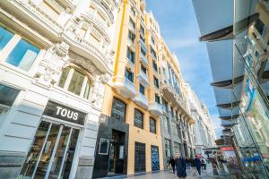 マドリードにあるLive it Madrid Gran Víaの建物前の道を歩く人々